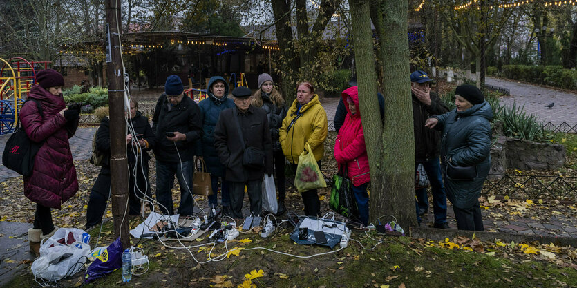 Menschen laden still ihre Mobiltelefone auf im Freien