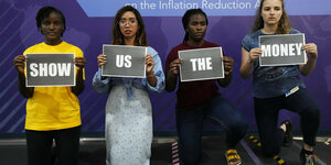 4 Aktivistinnen zeigen Plakate "Show- us -the- Money", sie knnien, jede trägt ein Wort