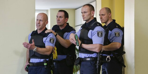 4 Polizisten stehen hintereinander und halten Taser in der Hand