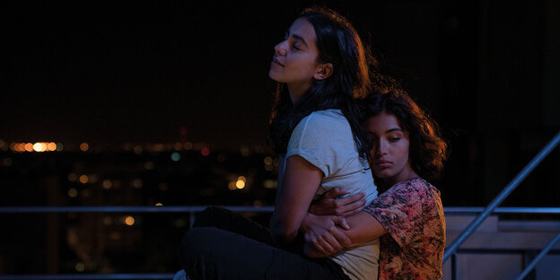 Zwei junge Frauen in einer Nachtszene, die sich umarmen
