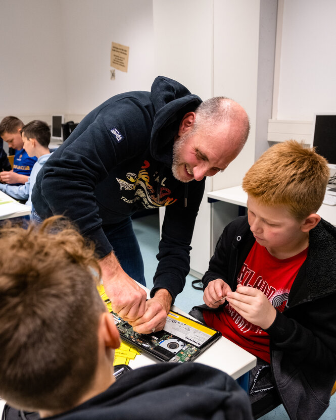 Ein Lehrer bastelt mit Schülern an Computertechnik.