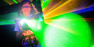 Ein Junge zielt mit einem "Phaser" grün leuchtend beim Lasertag auf andere Mitspieler