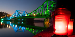 Bunt angestrahlte Glienicker Brücke mit zwei Grableuchten davor