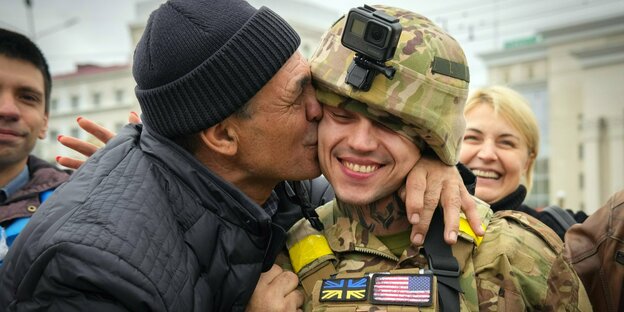 Ein Zivilist küsst einen Soldaten.