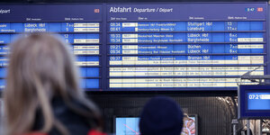 Menschen schauen auf eine Anzeigetafel im Hamburger Hauptbahnhof