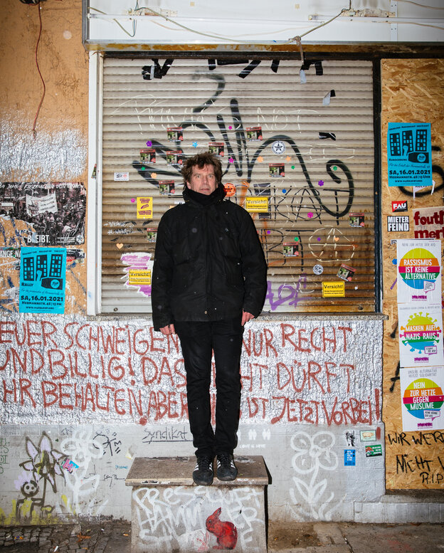 Ein Mann steht vor einem Haus mit verammeltem Fenster Ein Mann steht vor einem Haus mit verammeltem Fenster