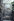 Wandbild in einem Berliner Hinterhof. Vor hellblauem Grund erhebt sich ein Säulenbogen, dahinter wachsen zwei Bäume mit schmalem Stamm und dichter Baumkrone in die Höhe. Im Hintergrund sind Häuser mit von Säulen gestützten Dächern zu sehen