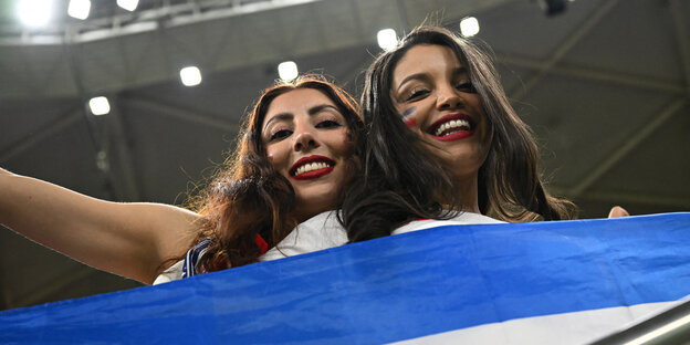 Zwei Frauen mit großer Nationalflagge vor sich