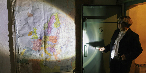 Eine Frau beleuchtet im Dunkeln eine alte Landkarte