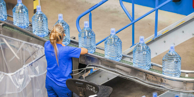Plastikflaschenabfüllung, eine Frau mit blauem Arbeitskittel