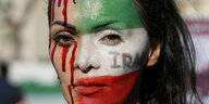 Eine mit Blut und einer iranischen Flagge geschminkte Frau.