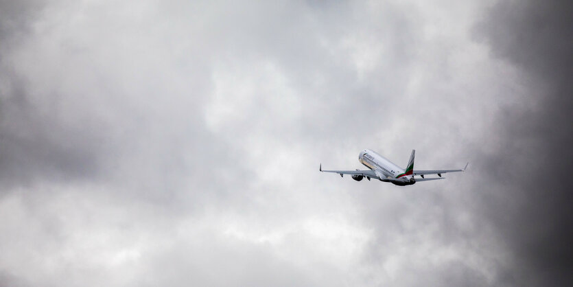 Ein Flugzeug fliegt in den grauen Wolkenhimmel