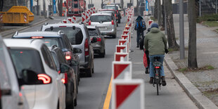 Straße mit Autos links und Radfahrenden rechts, dazwischen Warnbaken