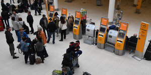 Menschen stehen mit Koffern an Terminals zum Check-in