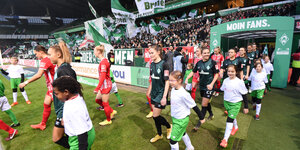 Die Teams aus Bremen und Freiburg laufen ins Weserstadion ein, im Hintergrund die Fankurve