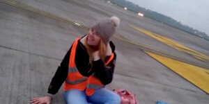 Aktivistin mit Pudelmütze und Warnweste auf dem Flugfeld