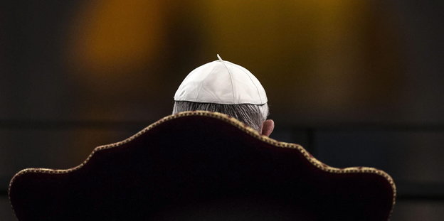 Papst Franziskus sitzt mit dem Rücken zur Kamera