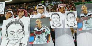 Katarer halten in einem WM-Stadion Bilder und Fotos von Mesut Özil hoch