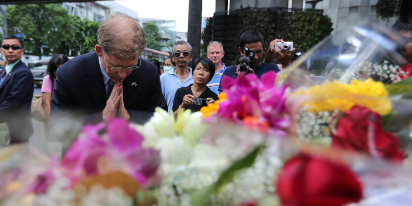 Ein Mann verbeugt sich vor Blumen