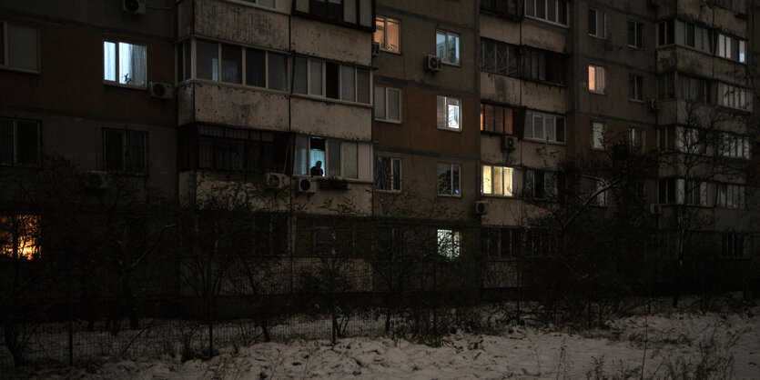 Wenige Fenster eines Wohnblocks sind erleuchtet