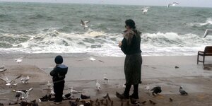 Eine Frau und ein Kind füttern Möwen am Strand