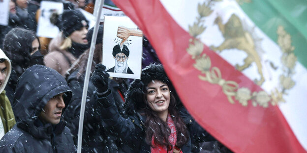 Eine Frau zeigt ein Bild des obersten Führers des Iran Ali Chamenei während der Demonstration Solidarität mit den Protesten im Iran