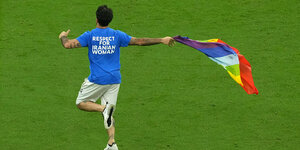 Mario Ferri läuft mit Regenbogenflagge über den Rasen, auf seinem Shirt steht „Respect for Iranian Woman“