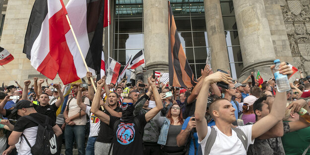 Protestierende, teils vermummt, schwenken Reichsflaggen auf den Treppen des Reichstagsgebäudes