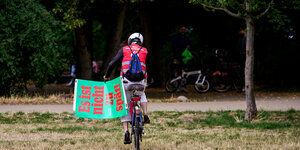 Das Bild zeigt einen Unterschriftensammler für "Berlin klimaneutral 2030" auf einem Fahrrad.