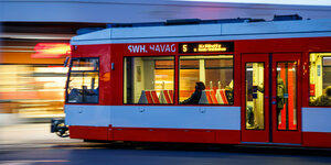 Fahrgäste sitzen im morgendlichen Berufsverkehr in einer Straßenbahn.