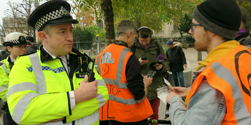 Ein Polizist und und eine Person mit Warnweste im Gespräch