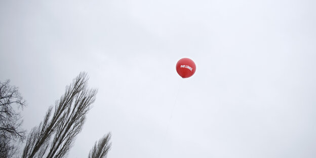 A red Left Party balloon flies in a cloudy sky