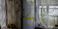 Auf einen Kühlschrank ist ein gelbes Z gesprüht, Vorhänge in einer Küche sind zugezogen