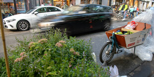 Ein geparktes Lastenrad neben einer befahrenen Straße.