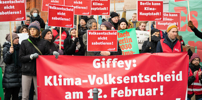 Menschen stehen mit Transparenten vor dem Roten Rathaus