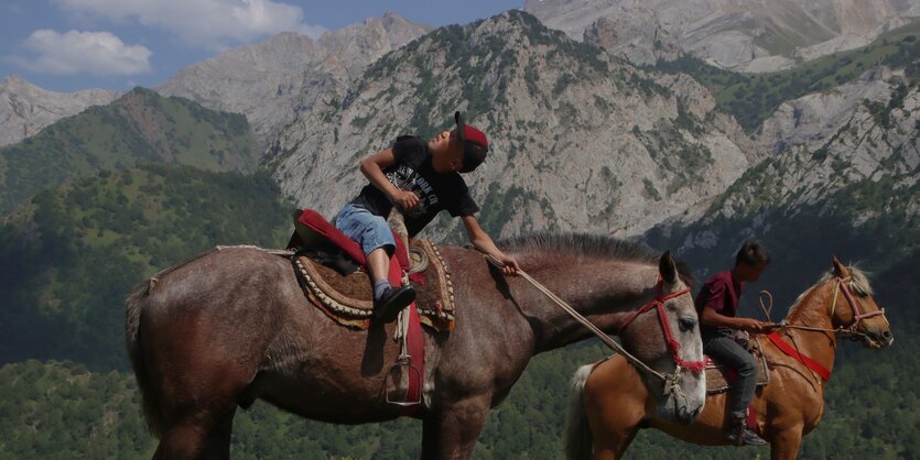 Ein Junge auf einem Pferd schaut einer Drohne nach