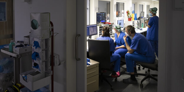 Pflegerinnen und Pfleger sitzen in einem Krankenhauszimmer