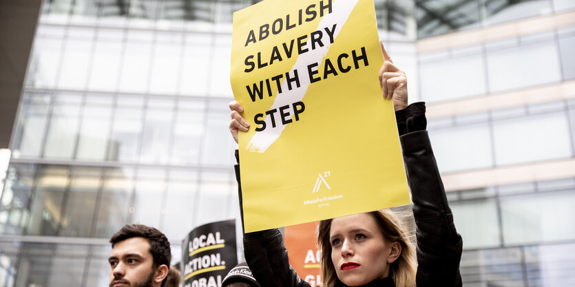 Eine Teilnehmerin des weltweiten «Walk For Freedom», einem Schweigemarsch gegen Menschenhandel, hält bei bei der Abschlussversammlung nahe dem Kurfürstendamm ein Plakat mit der Aufschrift «Abolish slavery with each step» (Sklaverei abschaffen mit jedem Schritt).