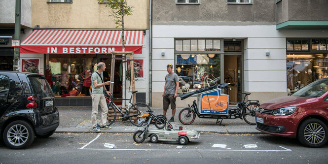 Ein Spielzeugauto und ein Kinderfahrrad stehen in einer Parklücke