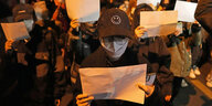 Protestierende halten leere Papierbätter hoch