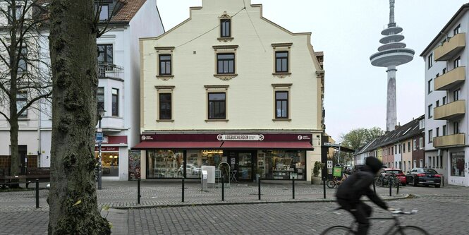 Aussenaufnahme der Buchhandlung "Logbuchladen" - ein Radler fährt vorbei, neblige Stimmung, das Schaufenster leuchtet