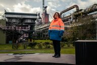 Bettina Hübschen steht in einer dicken Warnjacke vor dem Stahlwerk in Duisburg