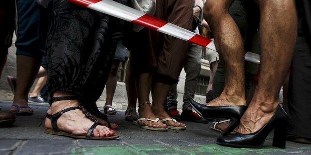 Ein Teilnehmer des High-Heel-Rennens in Madrid steht neben Zuschauern. Nur ihre Füße sind zu sehen.