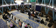 Muslime sitzen in Reihen auf einem Teppich in der Blauen Moschee