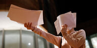 Eine Person hält ein Blatt Papier in die Höhe