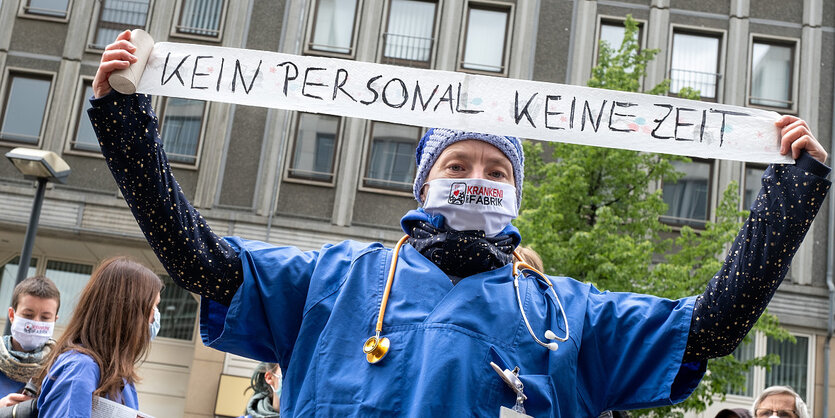 Ein Mann protestiert mit einem Transparent auf dem zu lesen ist "Kein personal-Keine Zeit"