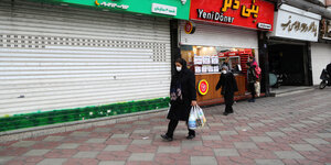Personen auf einer Straße vor geschlossenen Geschäften