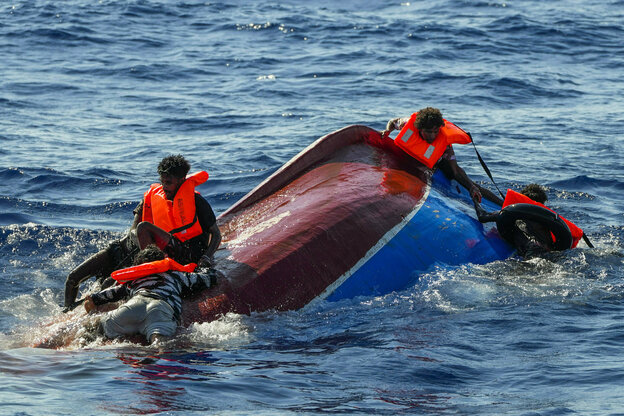 Menschen klammern sich im Meer an ein umgedrehtes Holzboot.