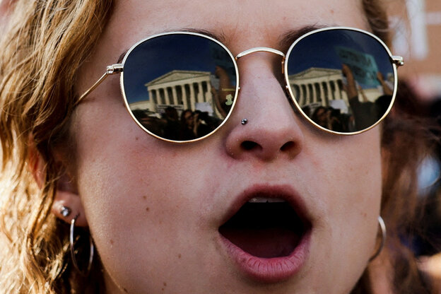 Frau mit Sonnebrille, in deren Gläsern sich das Haus des Obersten Gerichtshof spiegelt.