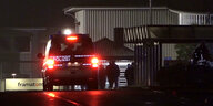 Ein Polizeifahrzeug in Dunkeln vor einem Werkstor